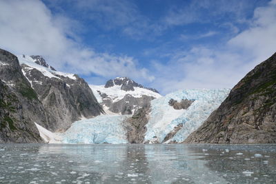 Scenic view of sea by mountains against sky