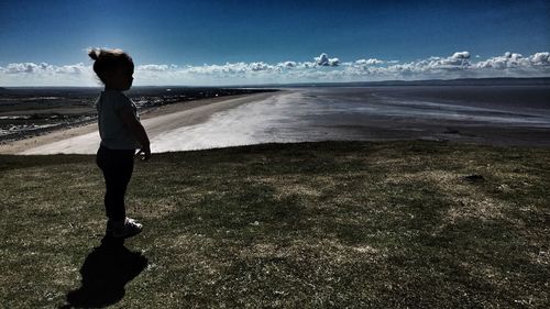 Girl standing at beach against sky