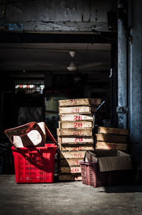 Stack of wooden crates by plastic chair in container in storage room