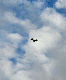 Low angle view of airplane flying against cloudy sky