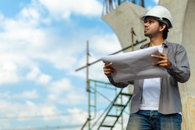 Man holding hat while standing outdoors