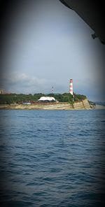 Lighthouse by sea against sky