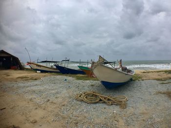 Boat moored on beach against sky