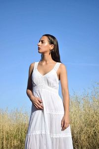 Young woman standing on field against clear blue sky