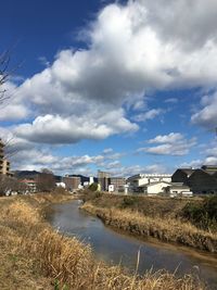 Houses by river amidst buildings against sky