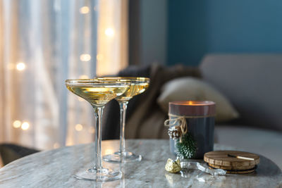 Two glasses of champagne against the background of a new year's garland in a cozy living room.