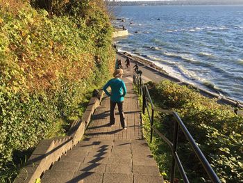 Rear view of woman standing on steps against sea