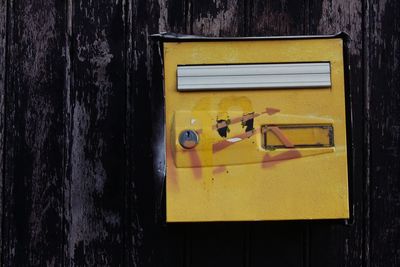 Close-up of yellow mailbox on wall