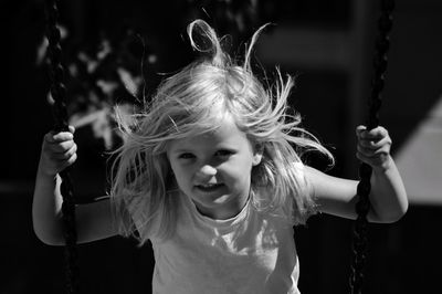 Portrait of cute girl sitting on swing