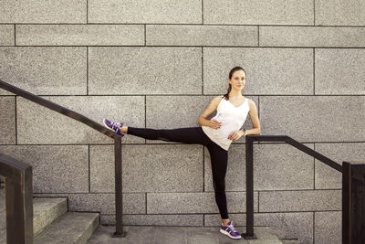 Woman standing on staircase against wall