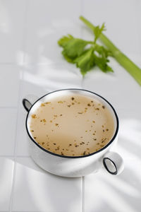 Healthy bone broth with spices in minsk on a white tile with a shadow pattern.