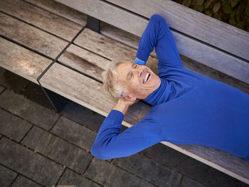 Elderly man laughing lying on bench