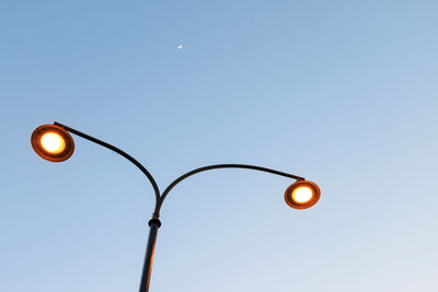 Low angle view of illuminated street light against sky at dusk