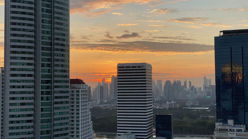 Modern buildings in city against sky during sunset