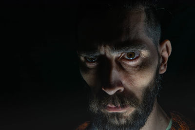 Close-up portrait of man against black background
