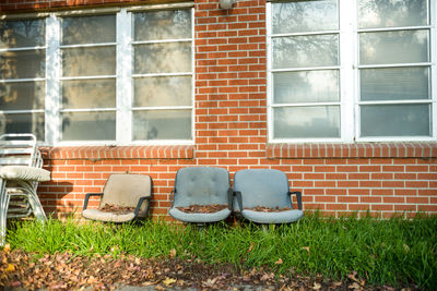 Abandoned chair against brick wall