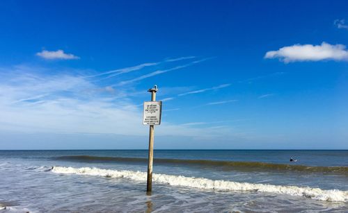 Information sign on beach against sky