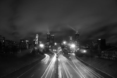 Illuminated light trails on road against sky at night