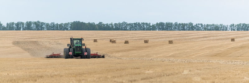 Panoramic view of tractor plowing field
