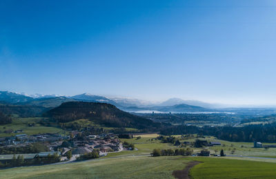 Scenic view of landscape and sea against blue sky