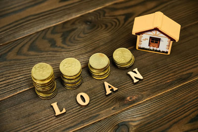 High angle view of coins with model home and loan text on table