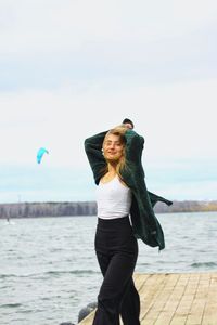 Young woman standing in sea against sky