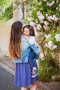 Mother and little handsome baby boy looking at bush with white roses