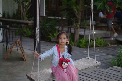 Portrait of cute girl sitting on the swing outdoors