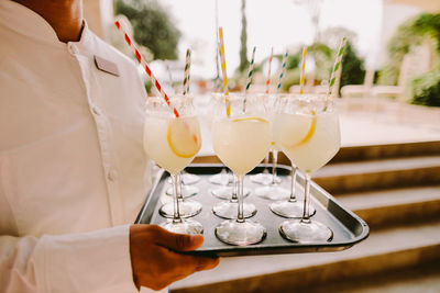 Midsection o waiter holding drinks in tray