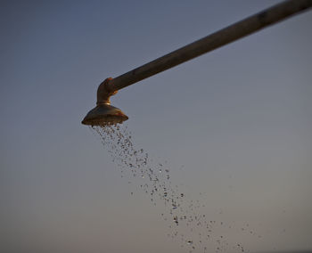 Low angle view of water drops on metal against sky