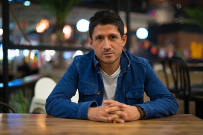 Portrait of man sitting on table in restaurant