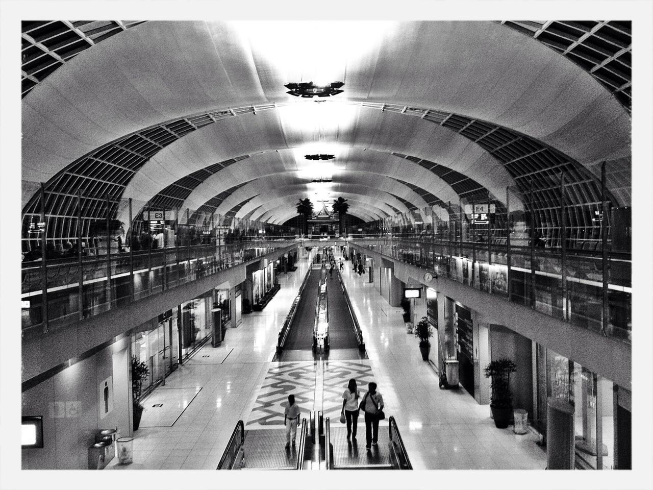 indoors, transfer print, ceiling, the way forward, large group of people, men, diminishing perspective, illuminated, walking, architecture, person, built structure, arch, auto post production filter, lighting equipment, lifestyles, corridor, vanishing point, transportation