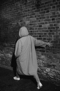 Rear view of woman standing against brick wall