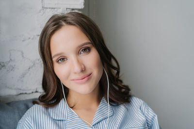 Portrait of a smiling young woman against wall