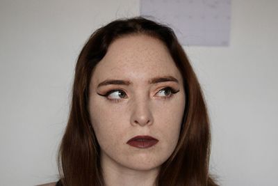 Close-up portrait of young woman against wall