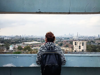 Rear view of woman standing by buildings against sky