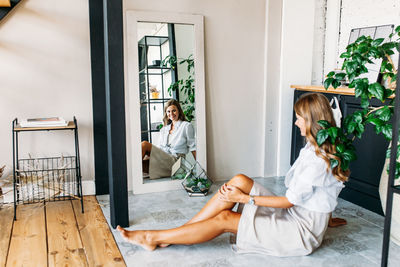 Woman sitting on potted plant at home