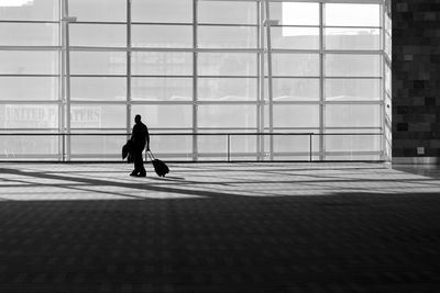 Silhouette man walking on building in city