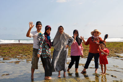 Portrait of people enjoying on beach against sky