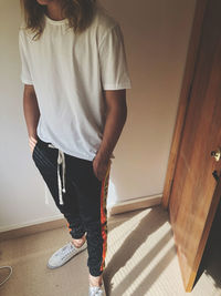 Low section of woman standing against wall at home