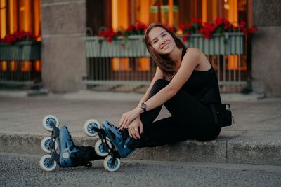 Portrait of young woman sitting on street in city