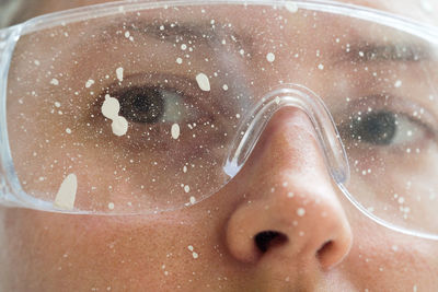 Close up of a woman face wearing protective glasses covered in paint