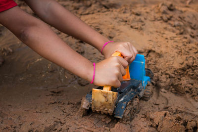 Low section of boy playing with toy on sand
