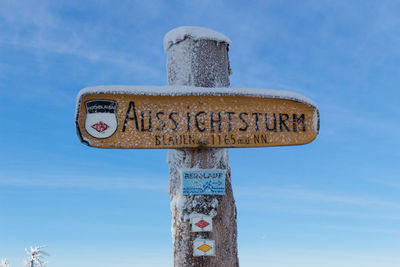 Close-up of roadsign against sky in winter
