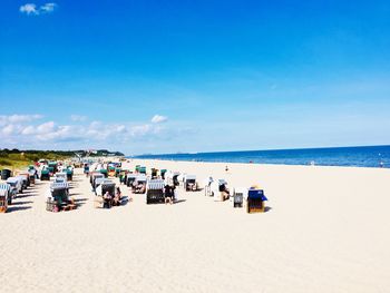 People on beach against blue sky