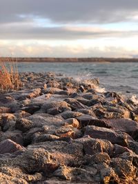 Rocks on shore against sky during sunset