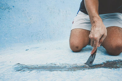 Low section of man sitting at shore