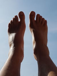 Low section of woman against sky in sunny day