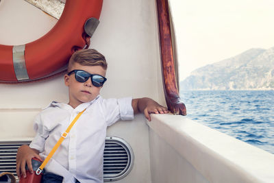 Portrait of cute boy wearing sunglasses while traveling in ship