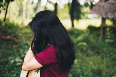 Side view of woman standing outdoors against trees